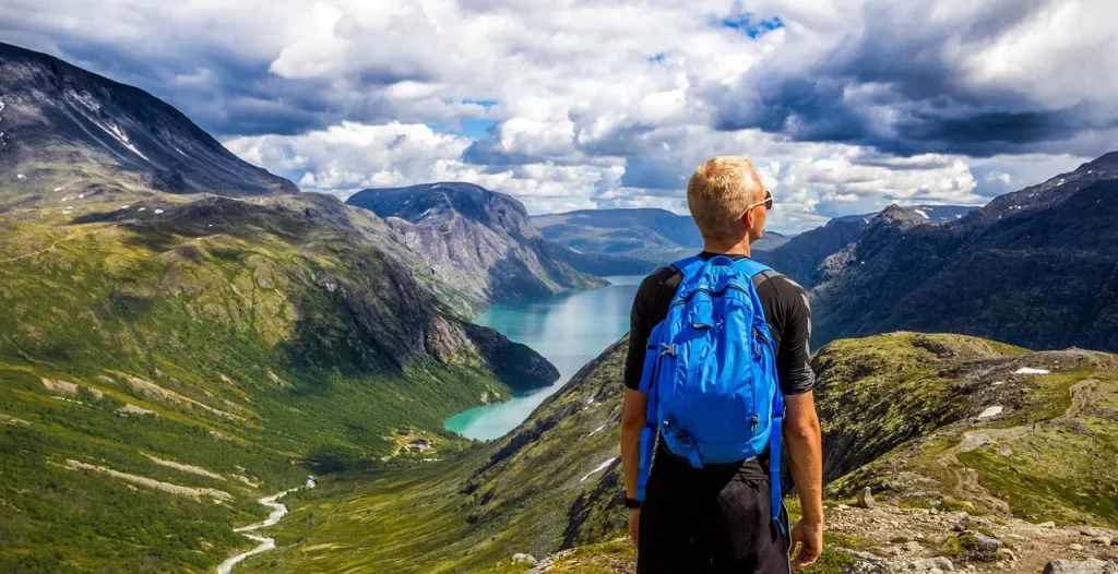 Wanderer mit blauem Rucksack über einem Fjord